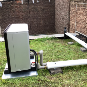 Außeneinheit einer Wärmepumpe Köln im begrünten Innenhof, fachgerecht installiert mit gedämmten Anschlussleitungen.