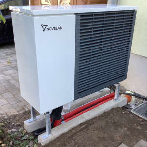 Kompakte Novelan-Außeneinheit einer Wärmepumpe Köln, installiert auf Fundament neben einem Wohnhaus.
